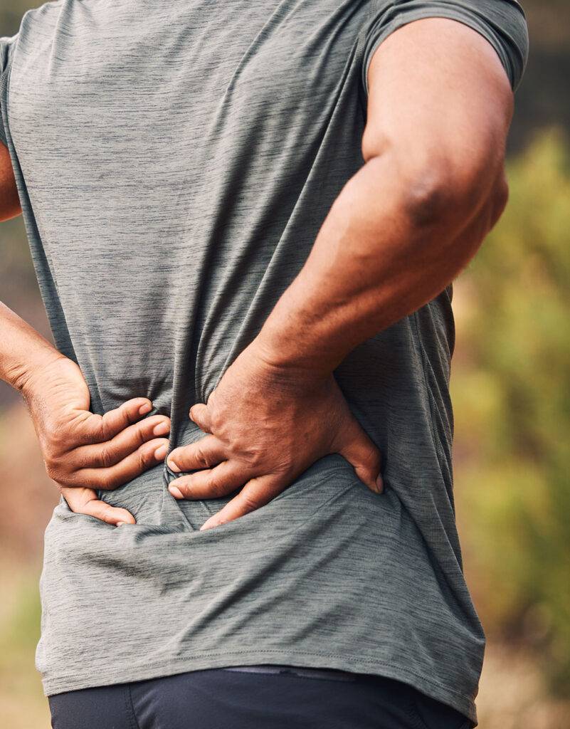 Patient with both hand on lower back in pain